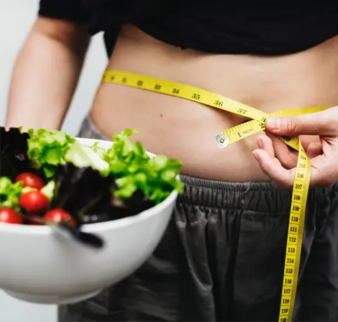 Wiehgt Loss Success in Wilmington DE at Lavish Wellness & Aesthetics. WOman holding a colorful salad and a measuring tape on her waist.